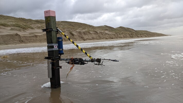 An Acoustic Doppler Velocimeter (ADV) mounted to a beach pole, with dune erosion in the background resulting from storm Pia in December 2023.
